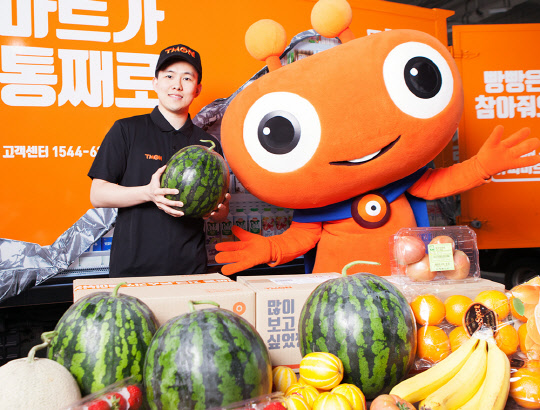 19일 티몬의 생필품 직배송 채널인 '슈퍼마트' 배송 기사와 캐릭터 '티모니'가 슈퍼마트의 과일상품을 선보이고 있다. <티몬 제공>